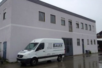 Hausmeisterservice Bauer Referenzen Landsberg - Weißer Lieferwagen vor grauem Gebäude in Landsberg