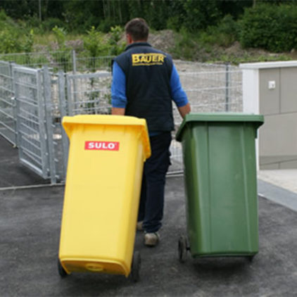 Hausmeisterservice Bauer - Mann mit einer gelben und grünen Mülltonne Hausmeisterservice Bauer - Mann mit einer gelben und grünen Mülltonne